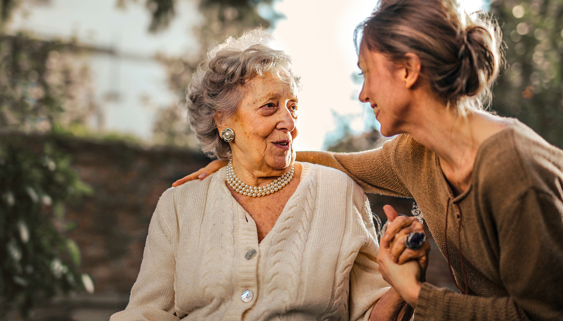 Auf dem Foto ist eine Seniorin im Gespräch mit einer Frau zu sehen.